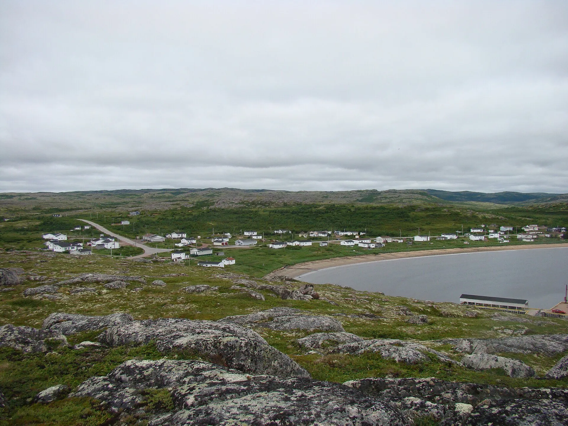 Pinware from the hill above: houses spread along the shore of its bay, with barrens in the foreground.