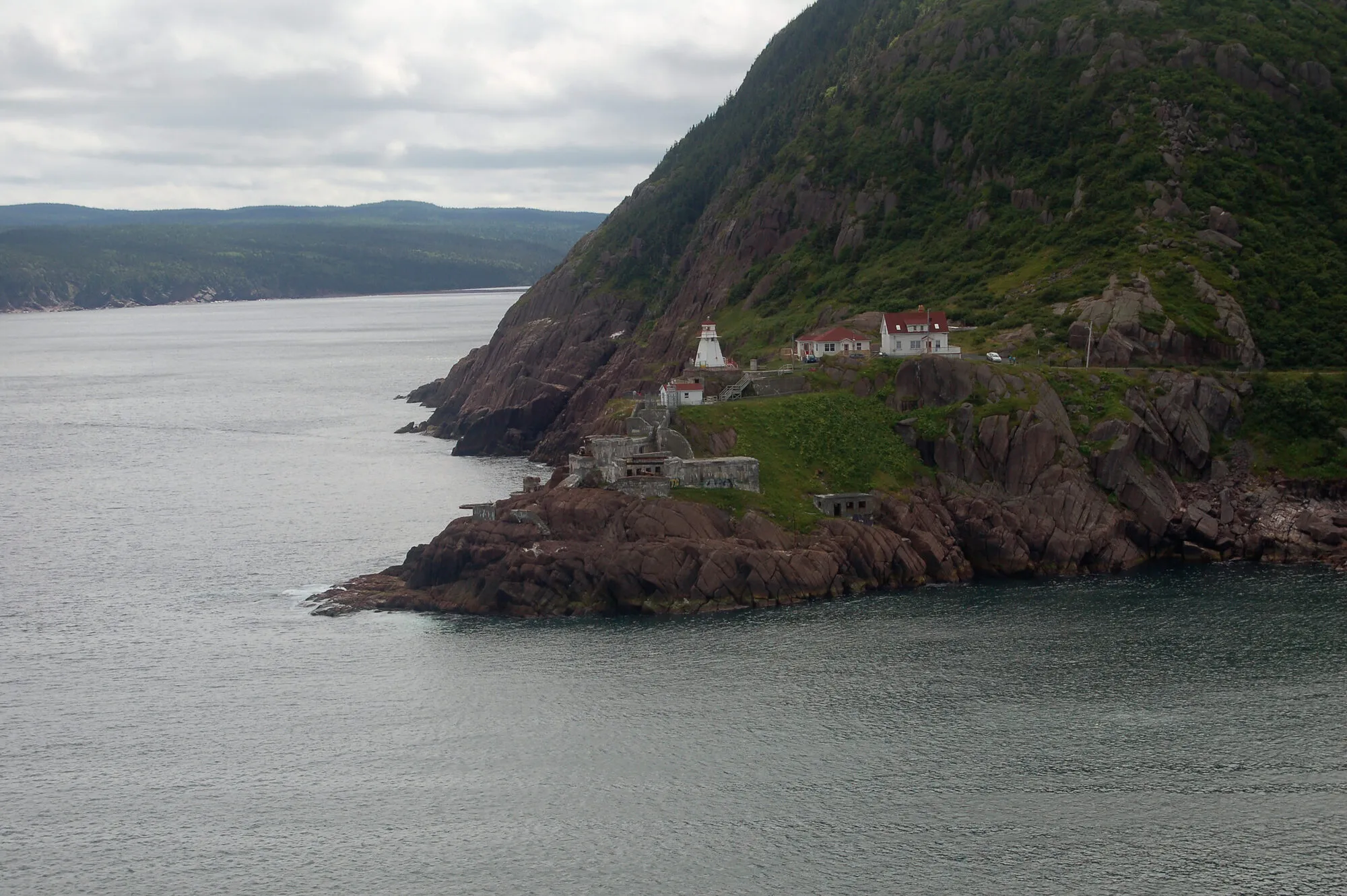 Fort Amherst's lighthouse and buildings at the foot of the cliffs across the Narrows, seen from North Head.