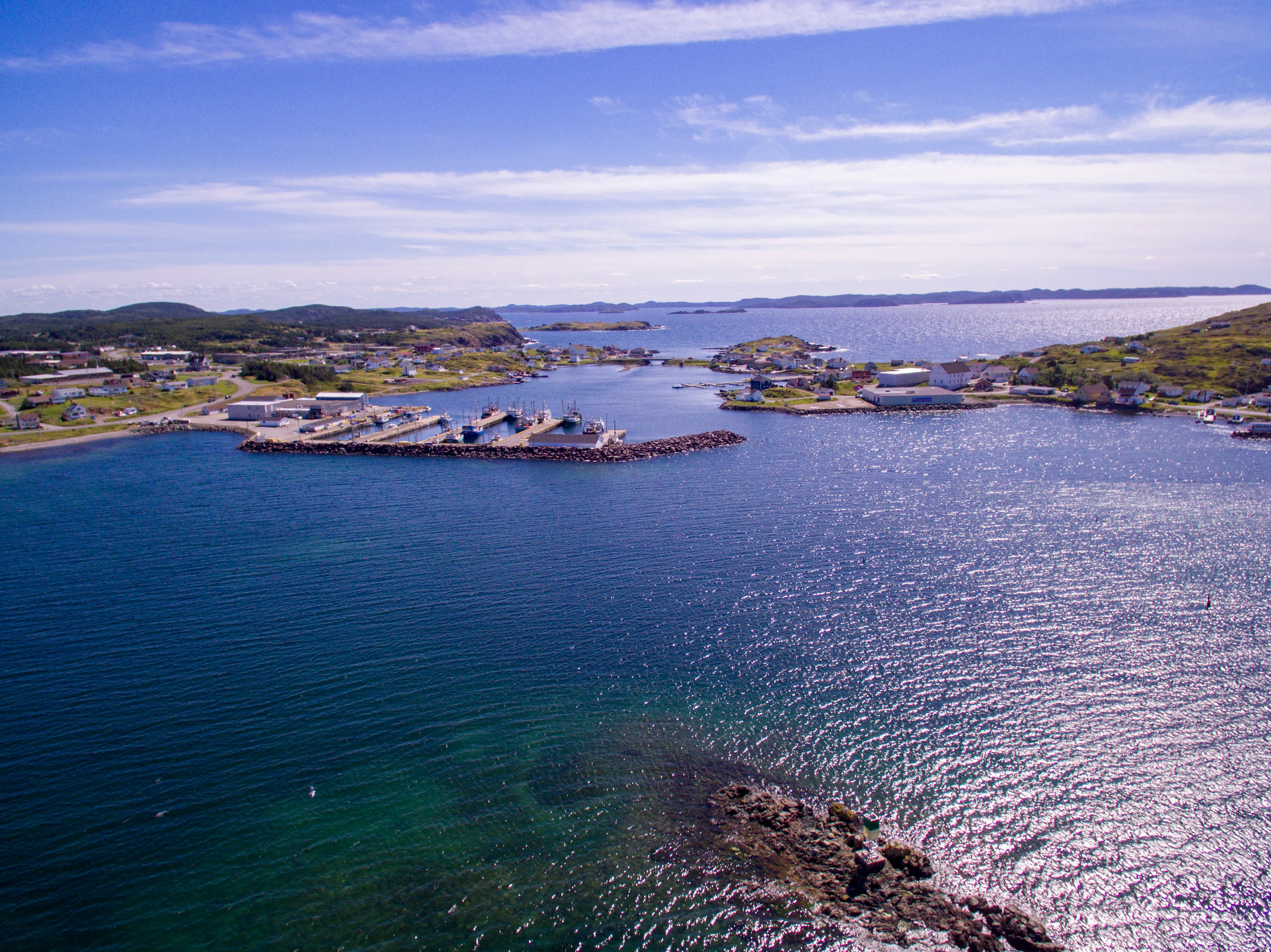 Twillingate's main harbour from the air - wharves, fishing boats and painted houses along the shore, the archipelago's islands behind.
