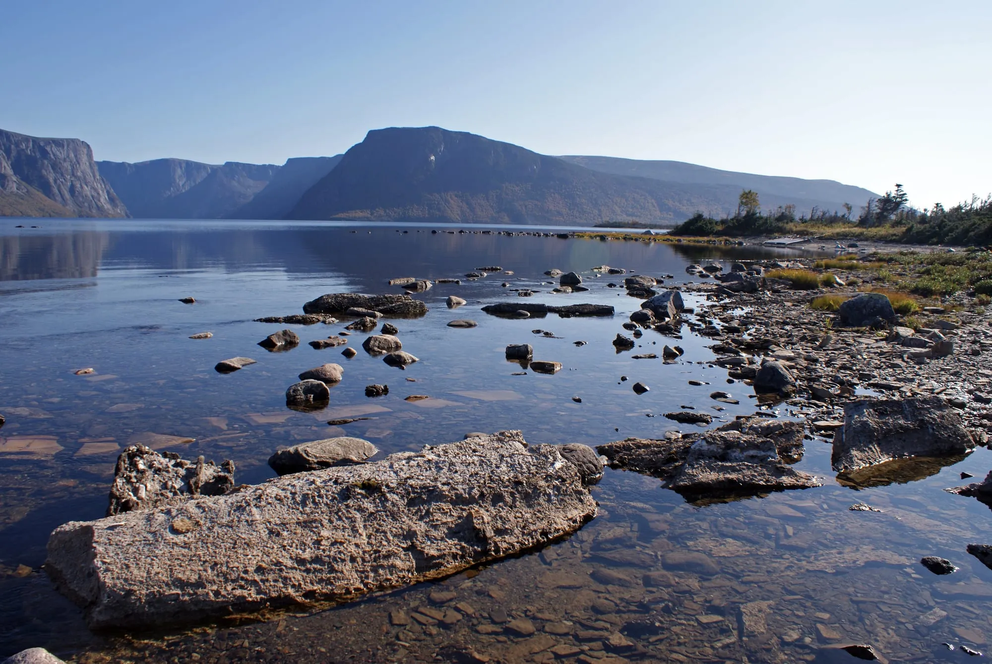 Western Brook Pond from its rocky shore at the end of the trail, the gorge's cliffs across the still water.