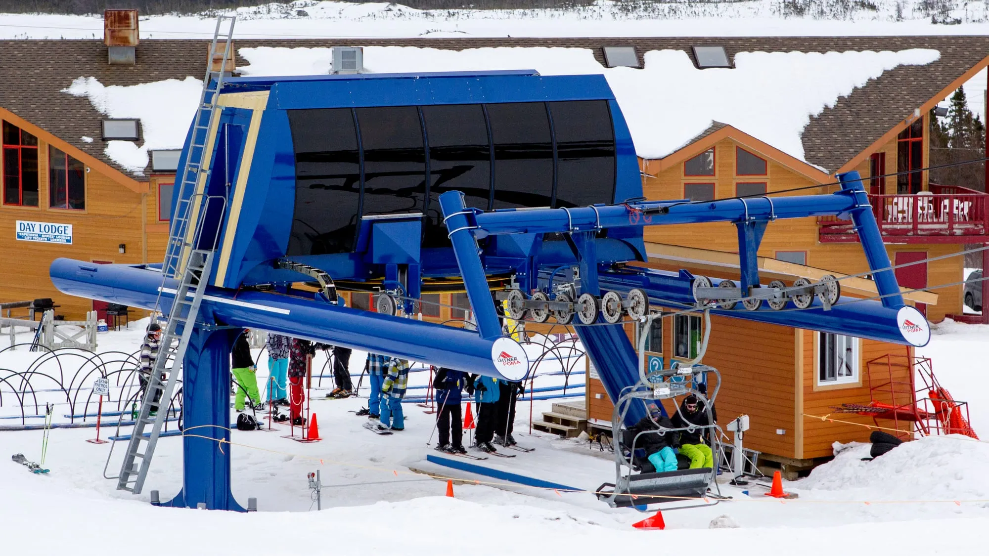 The blue chairlift terminal at White Hills Ski Resort, skiers queuing in the snow by the lodge.
