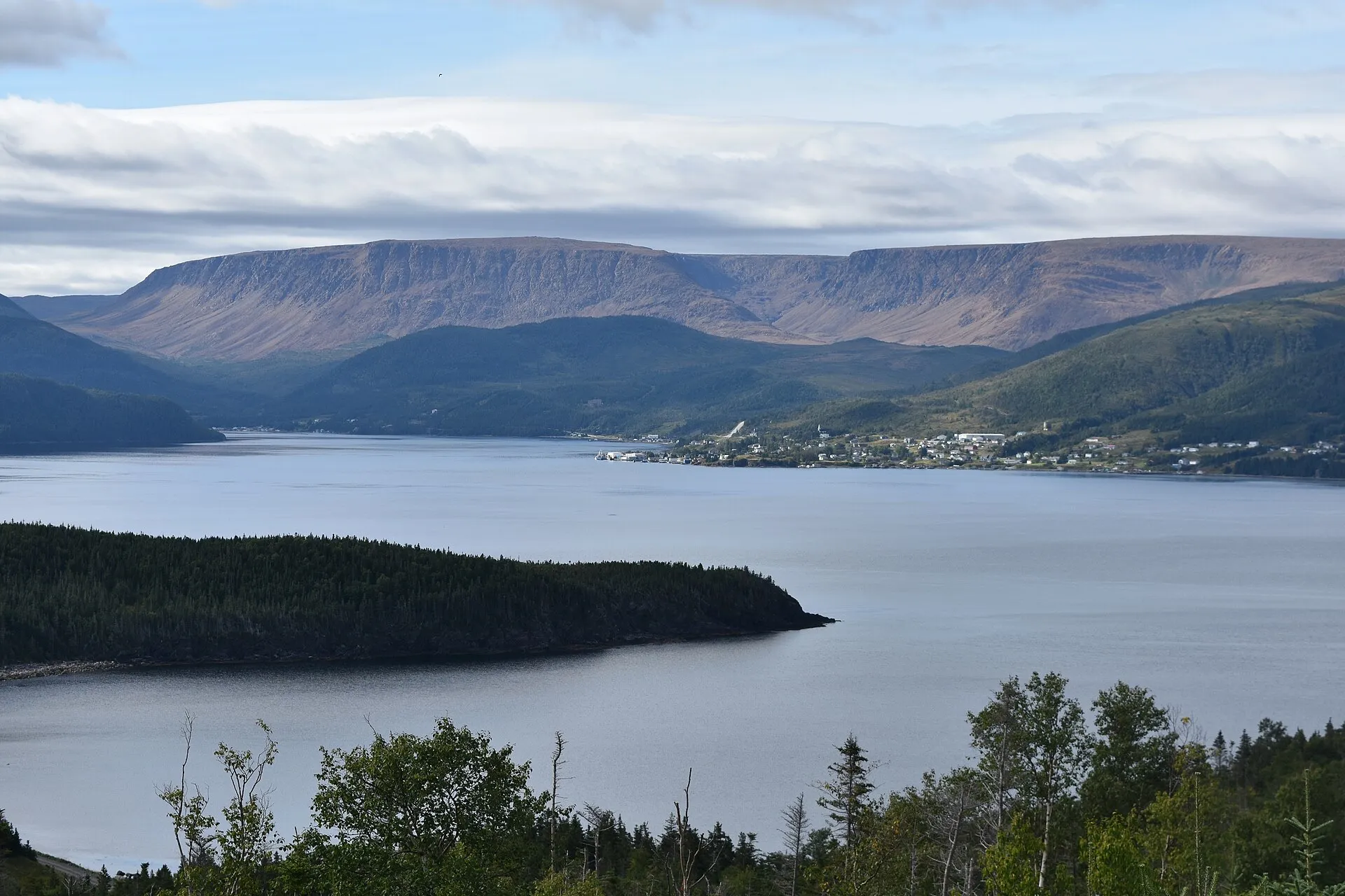 The flat-topped orange rock of the Tablelands rising behind Bonne Bay, with Woody Point's waterfront at its foot.