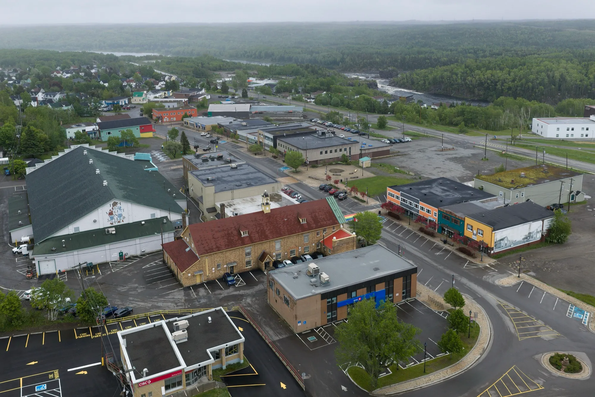 Aerial of downtown Grand Falls-Windsor with the Exploits River valley behind, overcast-bright.